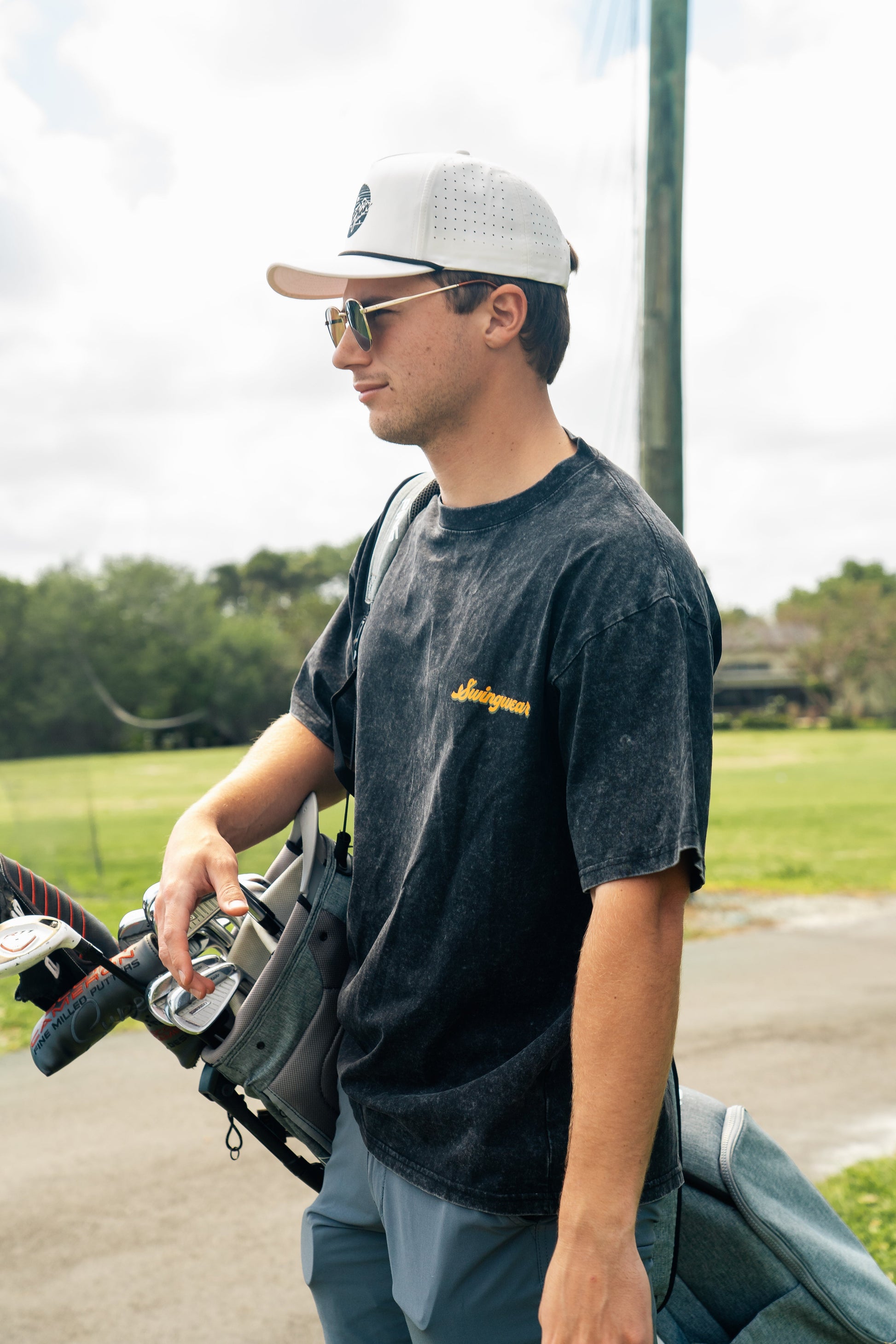 man with golf clubs wearing t-shirt