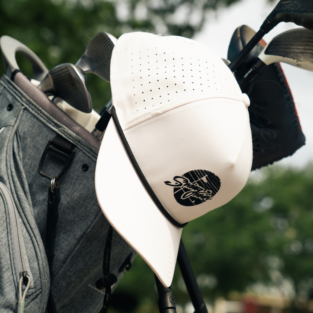 white swingwear golf hat hanging on golf club